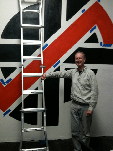 Dave King - stood in front of a recent wall size version of the Crass symbol