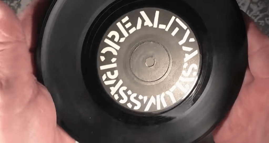The Reality Asylum single on Crass Records being held in two hands